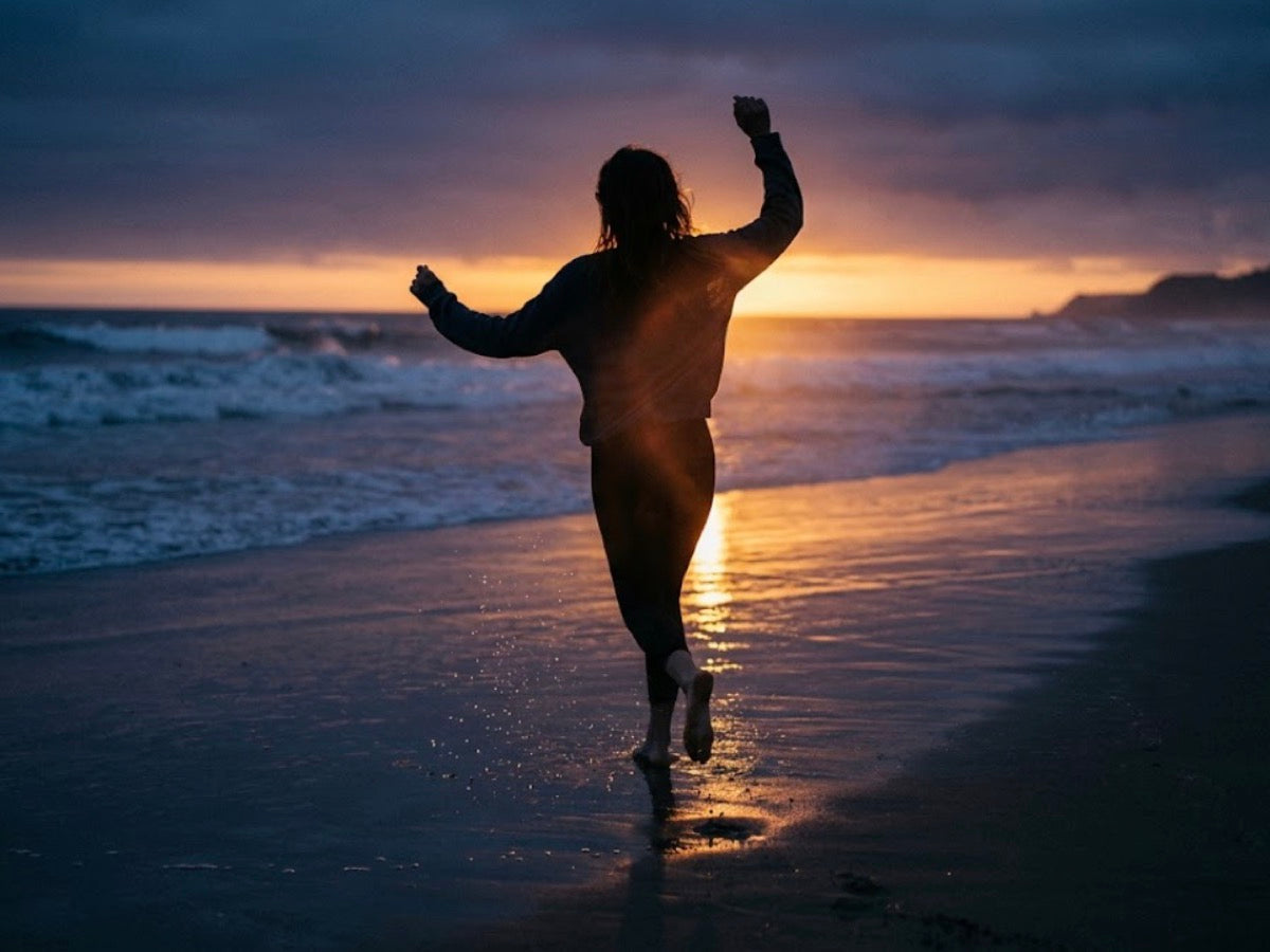 Woman dancing on a beach at sunset