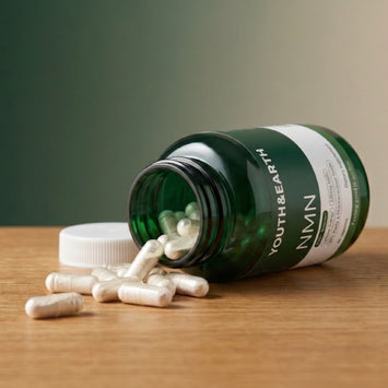 Youth & Earth NMN bottle tipped over with capsules spilling onto a wooden table