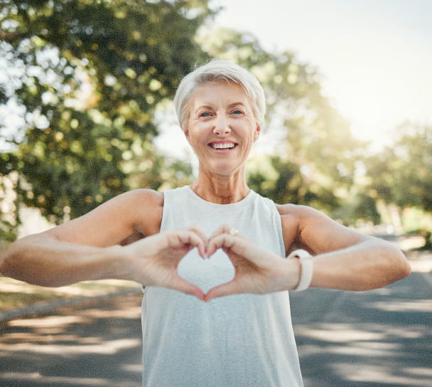 Woman making a heart shape with her hands outdoors