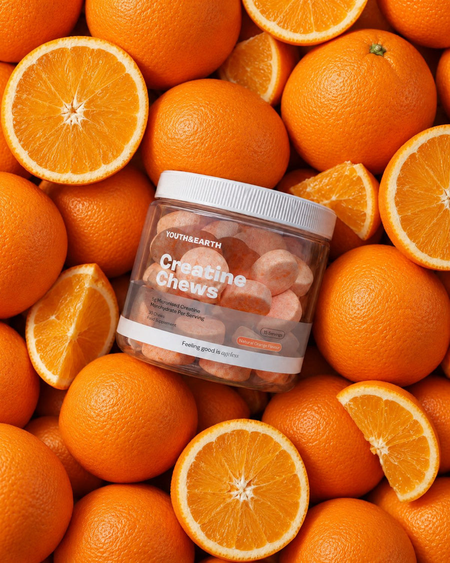 A jar of Creatine Chews resting among fresh oranges