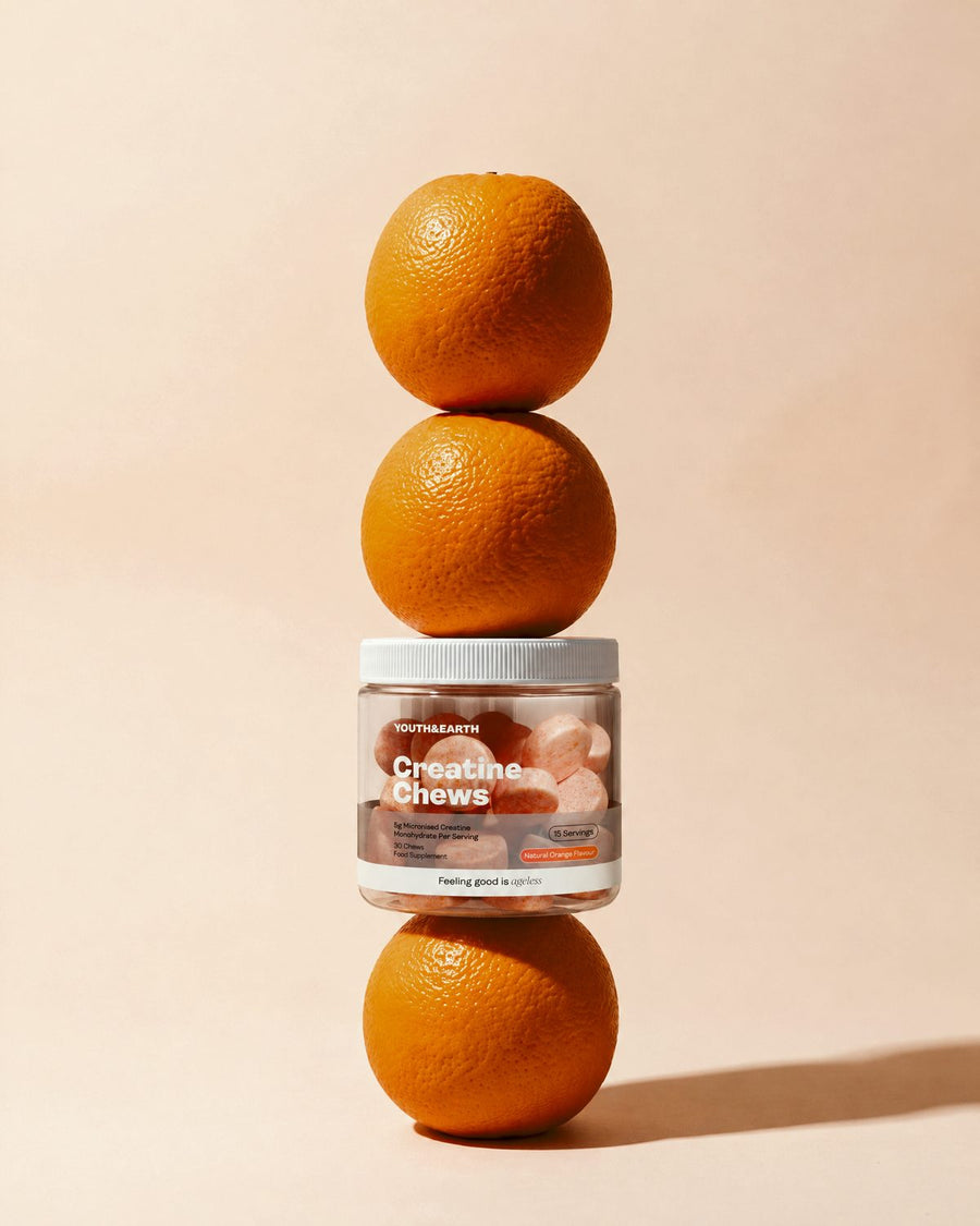 A jar of Creatine Chews balanced on a stack of oranges