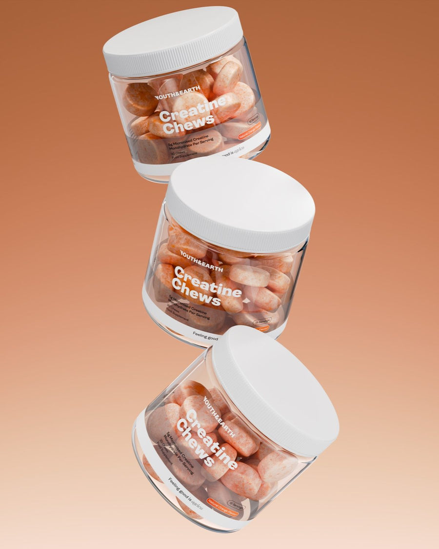 Three tubs of Creatine Chews floating one above the other against a warm orange backdrop